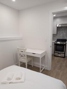 a white bedroom with a desk and a kitchen at Modern 2BR Suite Steps to SkyTrain in Vancouver
