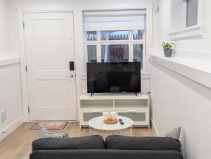 a living room with a couch and a tv at Modern 2BR Suite Steps to SkyTrain in Vancouver +8 photos