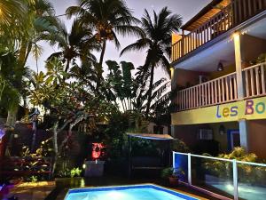 a swimming pool in front of a building with palm trees at Hôtel les Bougainvilliers in Saint-Gilles-les-Bains