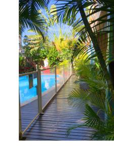 a wooden walkway with palm trees and a swimming pool at Hôtel les Bougainvilliers in Saint-Gilles-les-Bains +44 photos