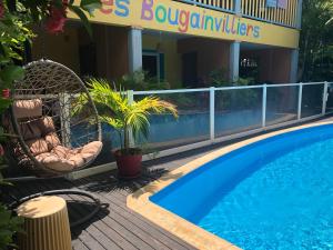 a resort with a swimming pool and chairs next to a building at Hôtel les Bougainvilliers in Saint-Gilles-les-Bains