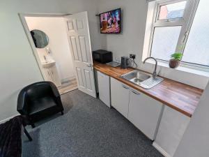 a small kitchen with a sink and a chair at Rose Studio - Self Contained Studio Flat in Oxford