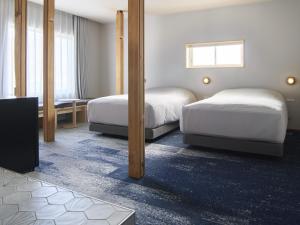 a hotel room with two beds and a television at Hotel Miyam Matsubarako in Yanaike