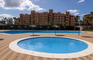 a large swimming pool with umbrellas in front of a building at Beachfront on Isla Canela in Punta del Caimán