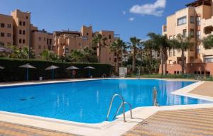 a large blue swimming pool with buildings in the background at Beachfront on Isla Canela in Punta del Caimán +5 photos