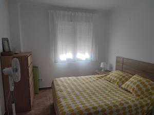 a bedroom with a bed with a checkered blanket and a window at Beachfront on Isla Canela in Punta del Caimán