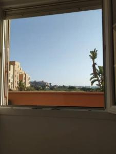 a window with a view of a palm tree and buildings at Beachfront on Isla Canela in Punta del Caimán