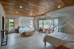 a bedroom with two beds and a wooden ceiling at Zambezi Drift Inn in Livingstone