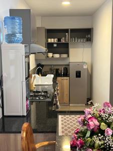 eine Küche mit Kühlschrank und einem Tisch mit Blumen in der Unterkunft Maisha Mapya in Gatimu