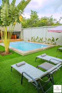 a pool with two lounge chairs and a palm tree at Kulala Stays Lodge in Livingstone