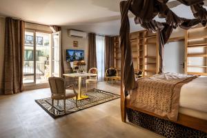 a bedroom with a canopy bed and a table and chairs at Le Clos Violette et Le 11 D'Aglaé - Appart' Hôtel de Charme Design de Luxe in L'Isle-sur-la-Sorgue