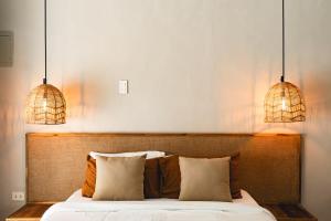 ein Schlafzimmer mit einem Bett und zwei Pendelleuchten in der Unterkunft Suenos Villas Siargao in General Luna
