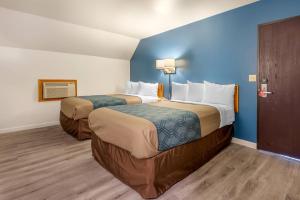 two beds in a hotel room with blue walls at Econo Lodge Saint Albans in Saint Albans