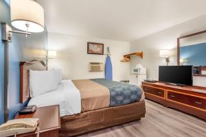 a hotel room with a bed and a flat screen tv at Econo Lodge Saint Albans in Saint Albans