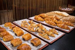 a table with several trays of pastries and croissants at Hotel Amaltea by Executive Sport in Lorca
