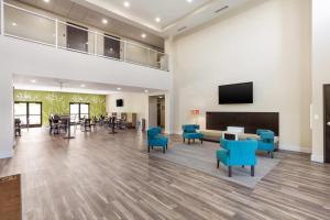 a waiting room with blue chairs and a flat screen tv at MainStay Suites Logan Ohio-Hocking Hills in Logan