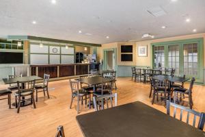 a dining room with tables and chairs and a kitchen at Econo Lodge Whitehall near Michigan's Adventure in Whitehall