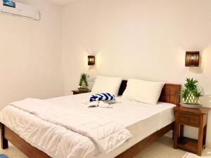 a bedroom with a bed with white sheets and two plants at The Kasbo in Unawatuna