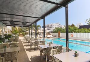a restaurant with tables and chairs next to a swimming pool at Pefkos City Hotel in Limassol