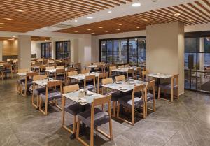 a dining room with tables and chairs and windows at Pefkos City Hotel in Limassol