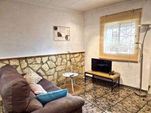 a living room with a couch and a stone wall at Casa Caloret - Playa y centro a 2 min in Vinarós
