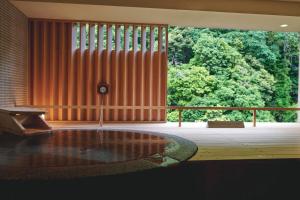 a room with a tub and a large window with trees at Hakone Pax Yoshino in Hakone