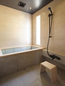 a bathroom with a tub and a bench and a shower at Hotel Miyam Matsubarako in Yanaike