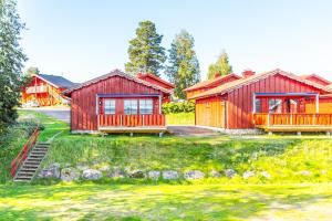 a home with two red buildings and a yard at Torsby Camping in Torsby
