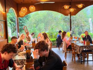a group of people sitting at tables in a restaurant at Forest Sunset hostel in Ninh Binh