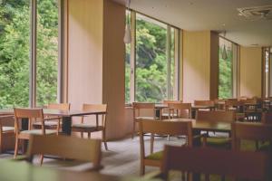 an empty room with tables and chairs and windows at Hakone Pax Yoshino in Hakone