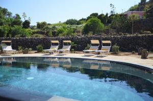 a group of four chairs and a swimming pool at Dammuso La Ginestra in Pantelleria