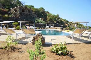 a swimming pool with two chairs next to at Dammuso La Ginestra in Pantelleria