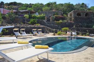 a swimming pool with lounge chairs and a table at Dammuso La Ginestra in Pantelleria