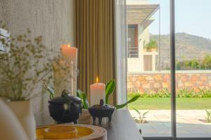 a table with two candles and a table with a window at SaffronStays Villa Rohi in Udaipur