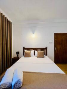 a bedroom with a large white bed with blue pillows at Velora Villa Tangalle in Tangalle