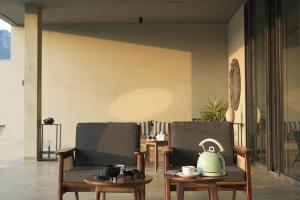 a living room with two chairs and a tea kettle on a table at SaffronStays Villa Rohi in Udaipur