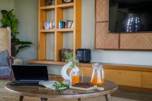 a coffee table with a laptop and orange juice at SaffronStays Villa Rohi in Udaipur +69 photos