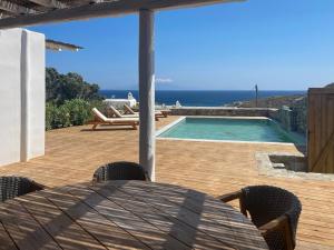 a patio with a table with an umbrella and a swimming pool at Emerald Bay 4BR with pool by Lia Beach in Mikonos
