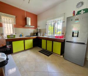 a kitchen with yellow and green cabinets and a refrigerator at Cozy 3BR Duplex with Pool & Garden View - Grand Gaube Getaway in Grande Gaube