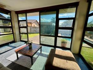 a living room with a table and large windows at One Birdswood in Richards Bay