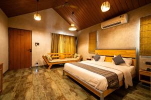 a bedroom with a large bed and a couch at Cape Nirvana, Backwater & Pool villa in Lavasa