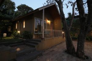 a small house with a porch and a tree at Cape Nirvana, Backwater & Pool villa in Lavasa