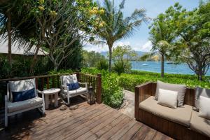 a wooden deck with chairs and a view of the water at Menjangan Dynasty Resort in Banyuwedang