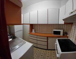 a small kitchen with white cabinets and a microwave at Appartamento IN CENTRO a Predazzo in Predazzo