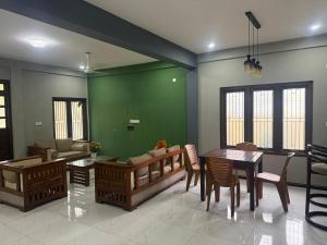 a living room with a table and a green wall at Palm Breeze Kokuvil G1 in Jaffna