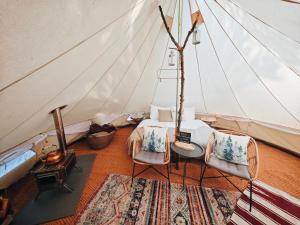 a room with a tent with a bed and chairs at Whispering Pines in Altsorgefeld