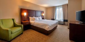 a bedroom with a bed and a chair and a television at Comfort Suites Goodyear-West Phoenix in Goodyear