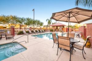 a patio with chairs and an umbrella next to a pool at Comfort Suites Goodyear-West Phoenix in Goodyear