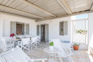 a patio with white chairs and a table at Aeraki Villas in Santa Maria
