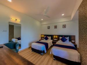 a hotel room with two beds and a couch at Zip By Spree Hotels Ranjangaon in Ranjangaon Ganpati +60 photos